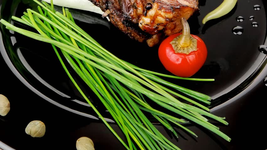 meat savory: roast ribs on black plate with peppers and chives