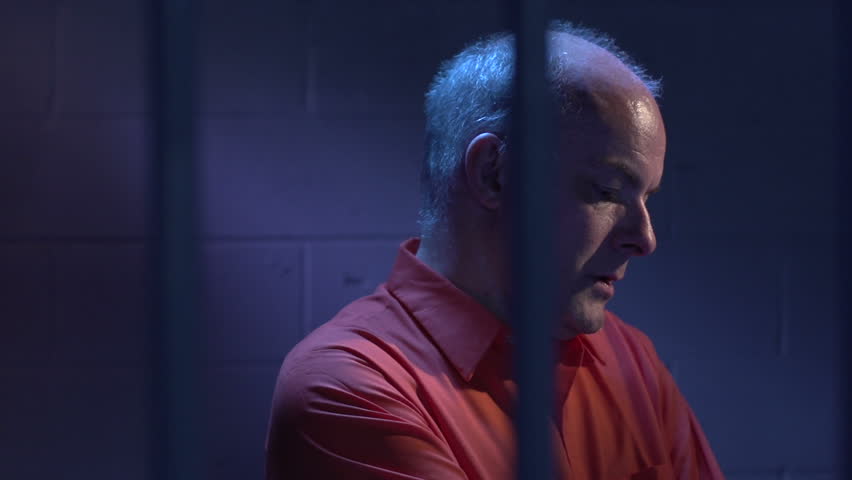 Man behind bars sitting in his cell
