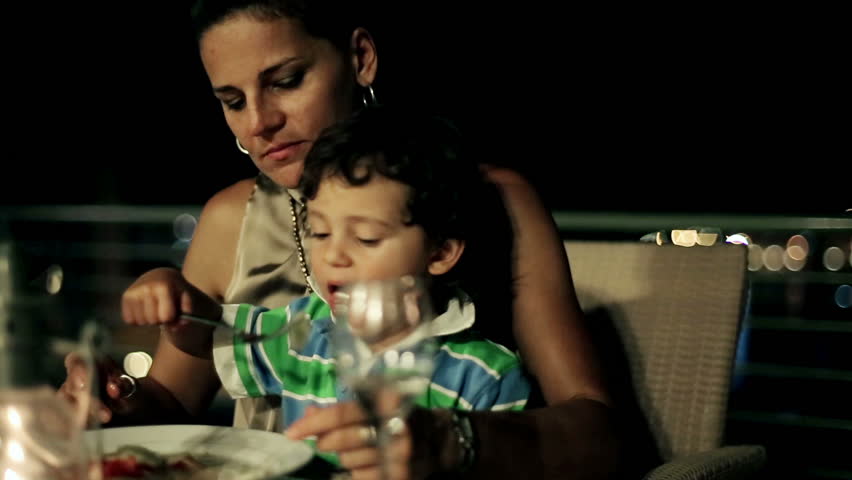Mother with her son eating dinner on the terrace at night, steadycam shot
