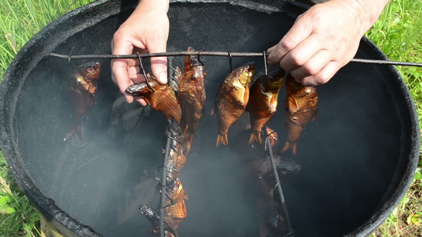hand take smoked fish hang on shank in smokehouse. delicacy gourmet diet food.