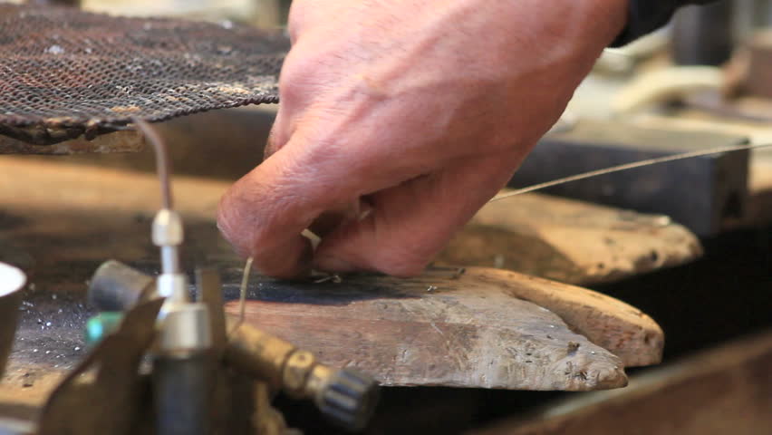 jewlery making: silversmith cutting a metal chord with a pliers
