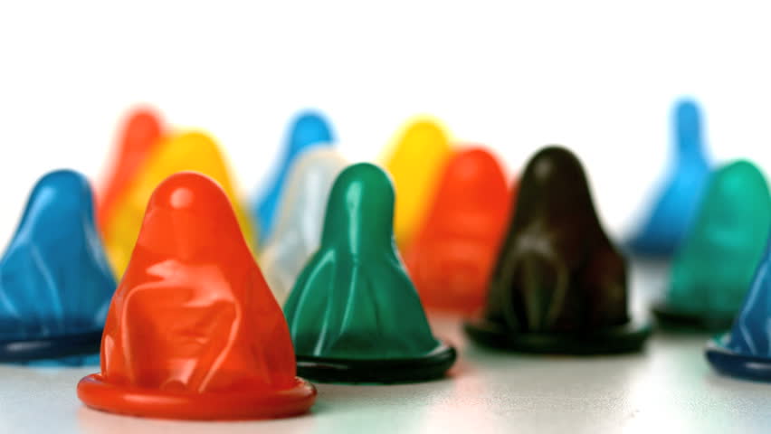 Yellow condom falling on surface with many condoms in slow motion