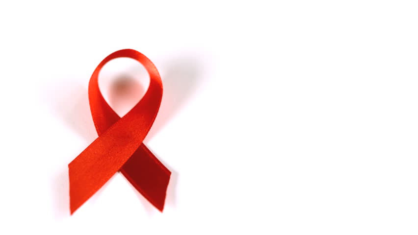 Condom falling over beside red ribbon in slow motion