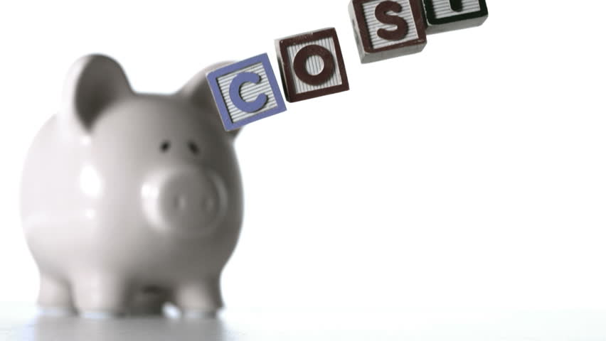 Blocks spelling cost dropping down beside a piggy bank in slow motion