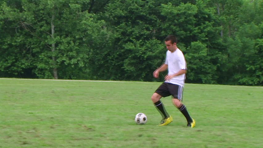 Young soccer player demonstrates footwork by dribbling ball, dolly shot.
