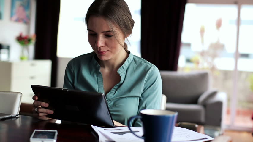 Businesswoman working on tablet computer in home
