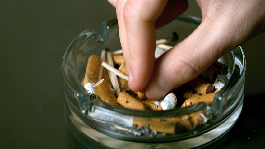 Hand putting cigarette out in ashtray in slow motion