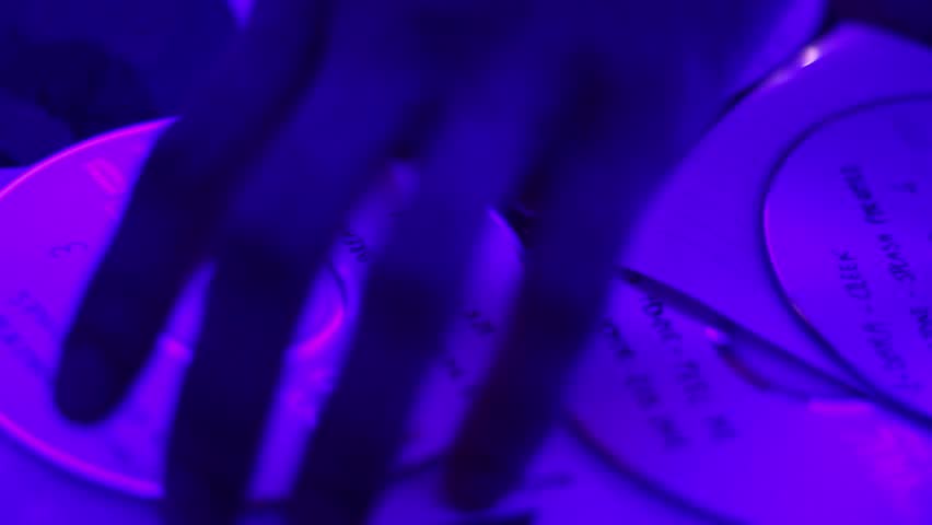 Hands of DJ take disks from the deck during performance in night club