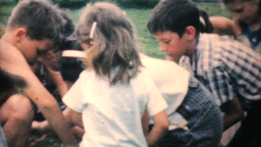 JOHNSTOWN, NEW YORK - JUNE 1964: Tons of kids enjoy fighting over lots of candy at a candy scramble at the park in 1964.