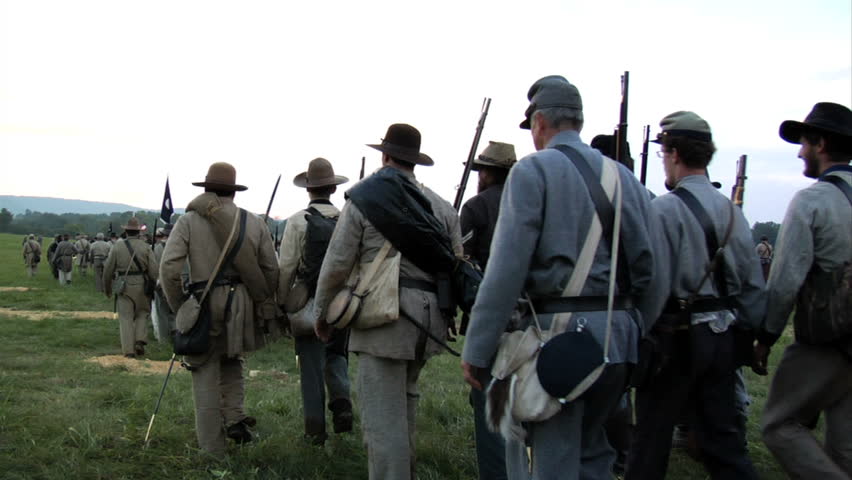 CHICKAMAUGA, GEORGIA - OCTOBER 2008 - large-scale, epic Civil War anniversary reenactment -- in the middle of battle.  Confederate Army marches across field, down hill on dirt road in column as sun sets. 