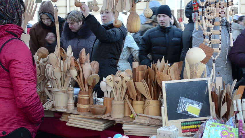 VILNIUS, LITHUANIA - MARCH 02: Woman sell various handmade wooden kitchen utensil tools and people choose goods in city market fair on March 02, 2012 in Vilnius.