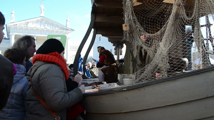 VILNIUS, LITHUANIA - MARCH 02: People buy fresh natural ecological fish from fisherman in wooden ship imitation in outdoor street market fair near cathedral square on March 02, 2012 in Vilnius.