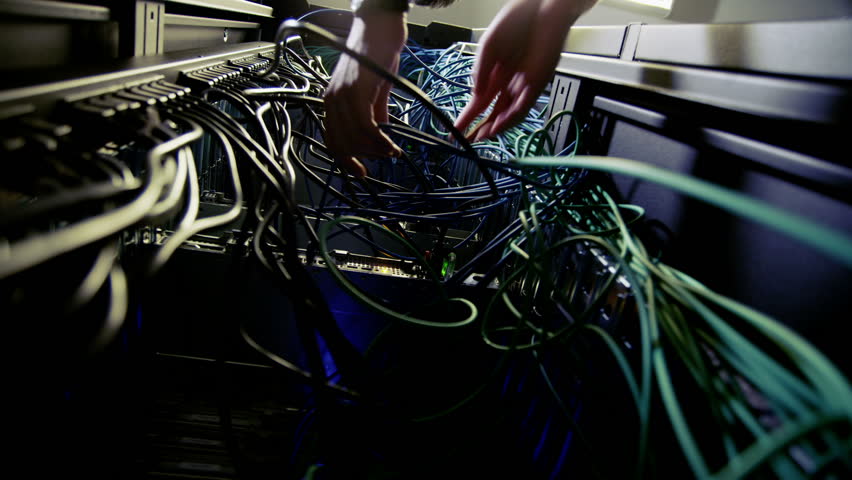 Male  IT engineer of Asian ethnicity carries out an inspection and maintenance procedure on servers and computers in a data center.