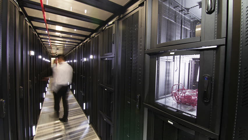 Group of  IT engineers of mixed ethnicity carry out an inspection and maintenance procedure on servers in a dark data center. In time lapse