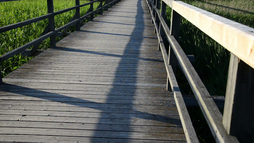 wooden board plank bridge with railings through lake and bicicle pass