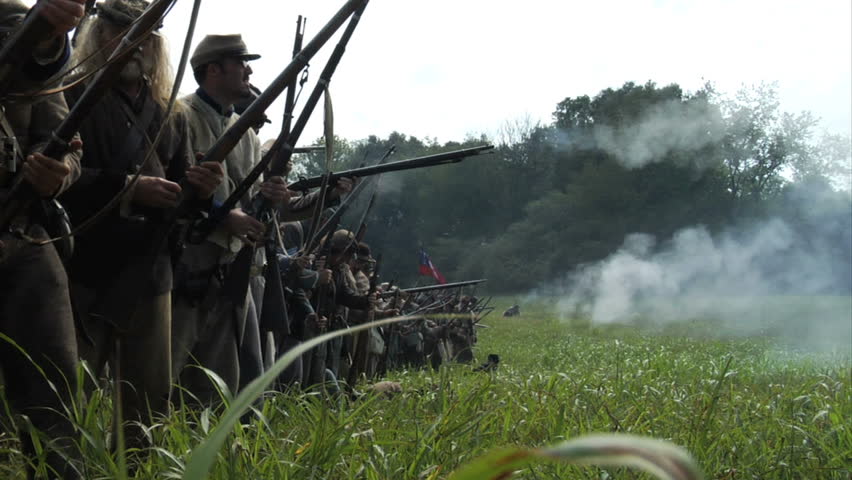 GEORGIA - OCTOBER 2008 - large-scale, epic Civil War anniversary reenactment -- in the middle of battle.  Line of Confederate infantry fires at will in line of battle as men try to rescue the wounded.