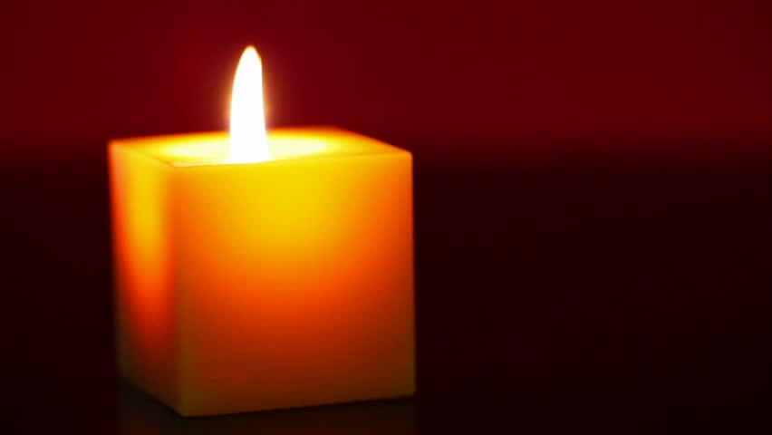 Burning candle against red background