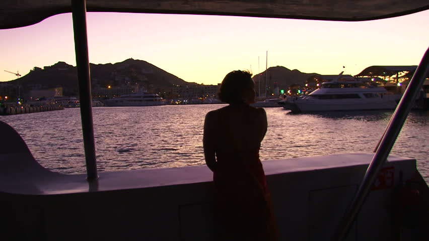 Model released woman enjoys the night scenery in Cabo San Lucas, Mexico on yacht.