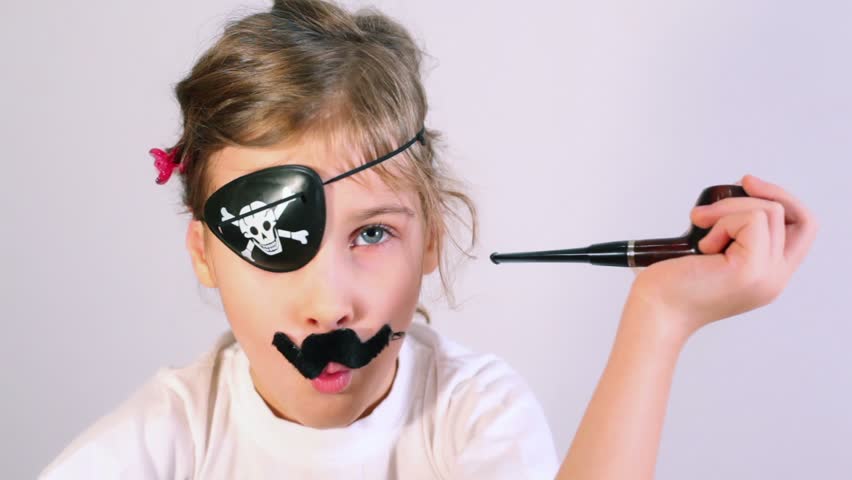 Little girl in white shirt imitates pipe smoking with fake mustaches and bandaged eye as pirate