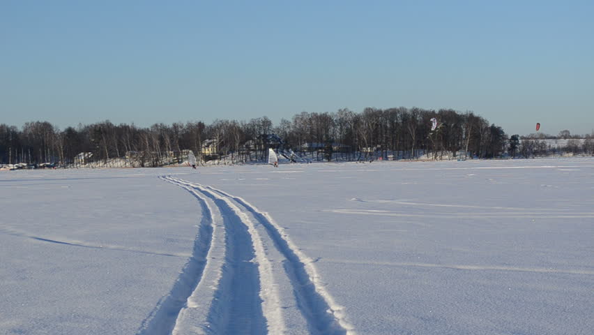 people kiteboarding and ice sailing on frozen lake in amazing cold winter day. modern recreation hobby.
