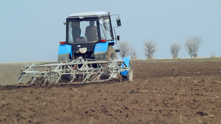 Tractor is working on farm field,plowing.