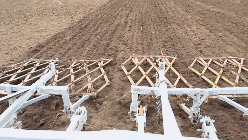 Close-up back view of tractor working on farm land,preparing field for sowing