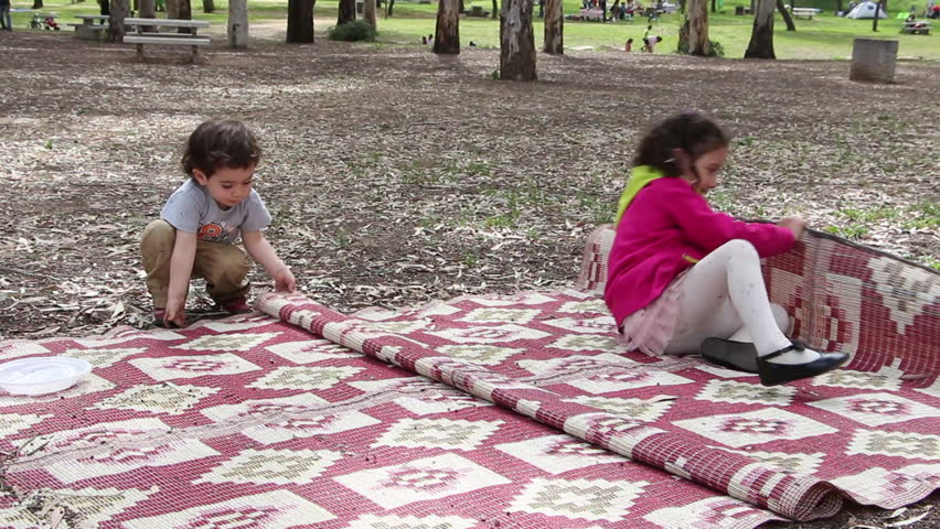 kids and dog play together rolling in a camping blanket