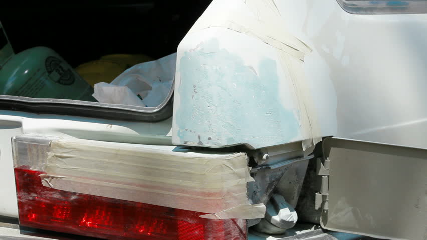 Repairman is smearing putty on car damaged surface.