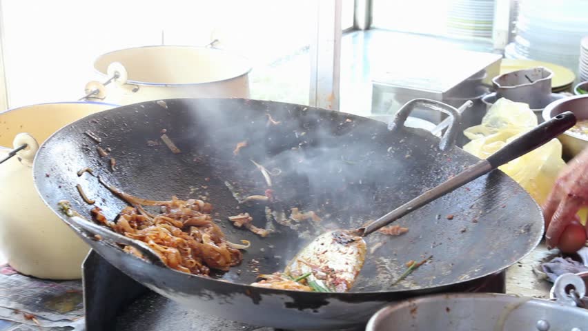 Street Vendor Hawker Cooking Yellow and White Noodles also known as Char Kway Teow with Dark Sweet Soy Sauce, Prawns, Bean Sprouts and Eggs in a Large Cast Iron Wok 1080p