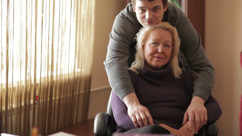 Thirty-year-old son hugs his mother looking to the camera.