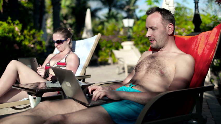 Young couple lying on sunbed using technology
