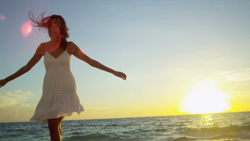 Pretty girl in sundress reveling being alone by ocean at sunrise on beach vacation shot on RED EPIC