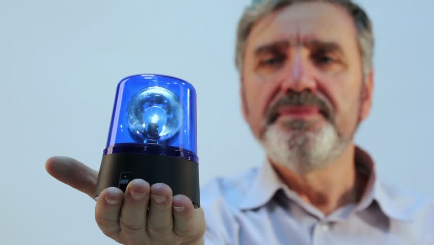 Aged man with beard holds blue flasher on hand, focus on blinker