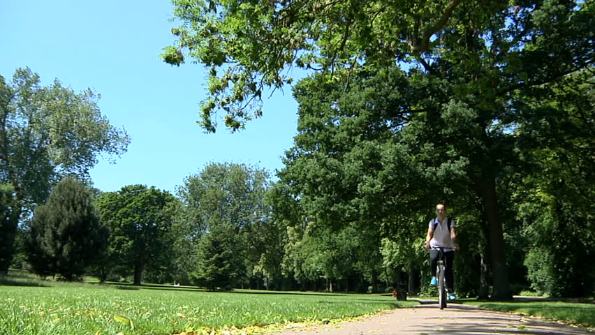 A student cycling along a path with trees