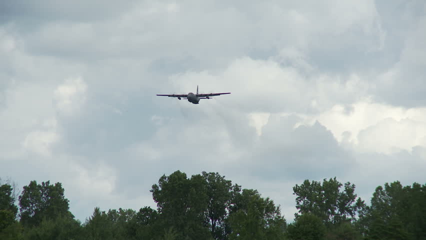 Lockheed Hercules military transport aircraft flying with rear cargo door open.