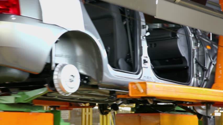 Conveyor transporter transfers unfinished car, closeup view at factory workshop