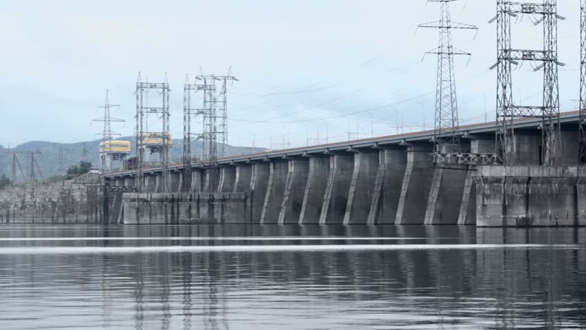 Traffic at dam of Hydroelectric power station on river, pillars with high-voltage wires