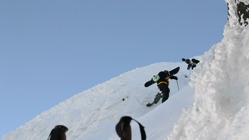 Free ride skiers hiking up steep slope.