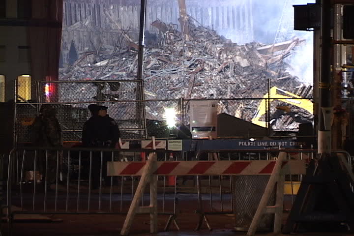 NEW YORK CITY - SEPTEMBER 28, 2001: Smoke rising from floodlit World Trade Center rubble, seen behind fence and barricades.