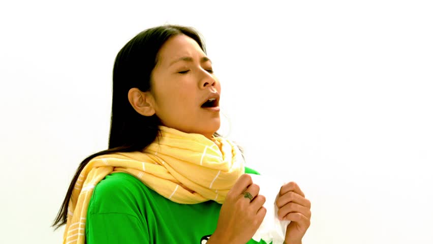 Asian woman in green tee shirt and yellow scarf sneezing in slow motion on white background