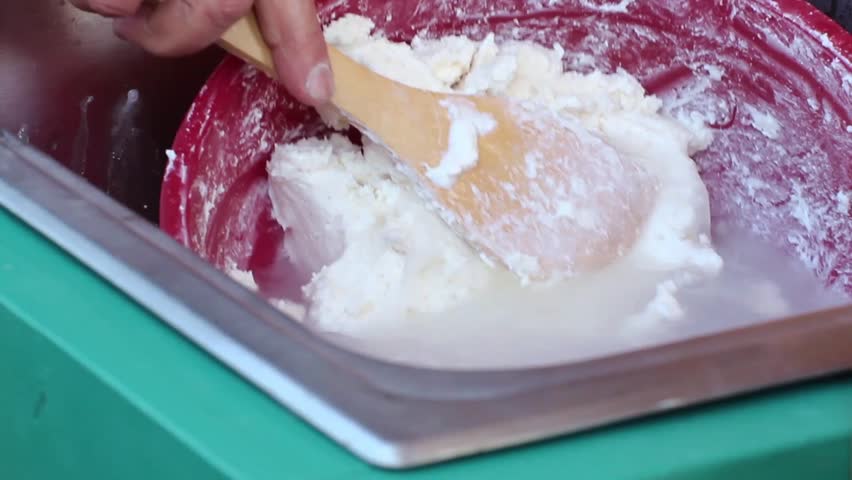 Hands making butter in red bowl