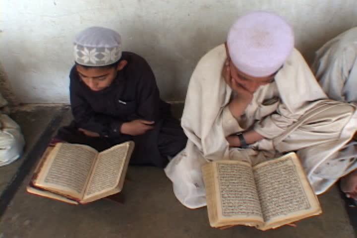 PESHAWAR, PAKISTAN - NOVEMBER 01, 2001: Two boys in Muslim dress rock back and forth as they read the Koran.