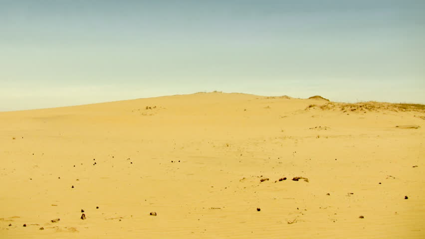 Man in desert walking on the horizon, stopping on the top of dune and waving one`s hand, HD