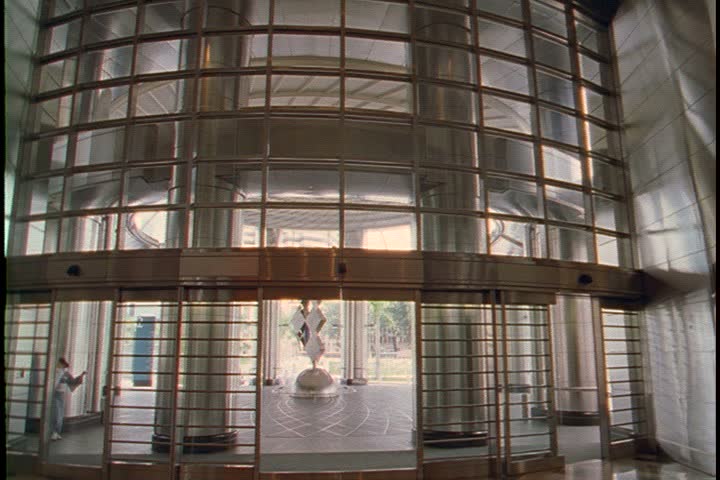 KUALA LUMPUR - AUGUST 22, 2006: Petronas Towers interior lobby; MS curved tiled wall, pan right past CU brass pillar to CU big glass entrance and doors. 