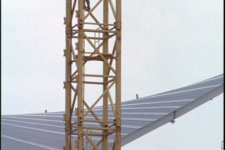 KUALA LUMPUR - OCTOBER 25, 1999: Kuala Lumpur construction site; WS worker in hard hat climbs down crane rigging.