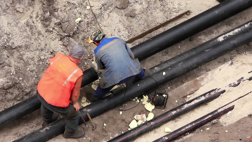Workers in pipeline trench reconstruct hot water supply system by new technology