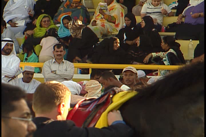 DUBAI - NOVEMBER 02, 2001: General views of Jebel Ali Race Course; MS seen through a few spectators, wreath is placed around winning horse, horse shakes of wreath and is led away.