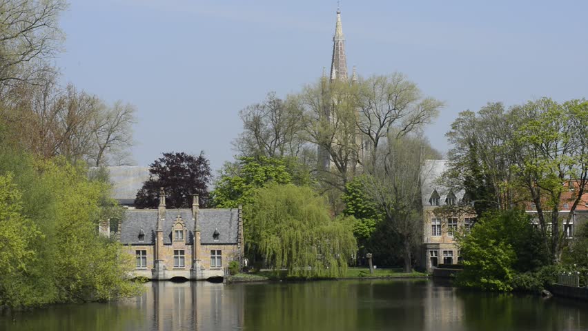 Minnewater lake (Lake of Love) in Bruges, Belgium: still footage of the Sluice House (Sashuis) on the lake and Church of Our Lady