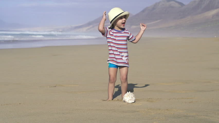 Happy kid with beautiful big seashell on the beach
