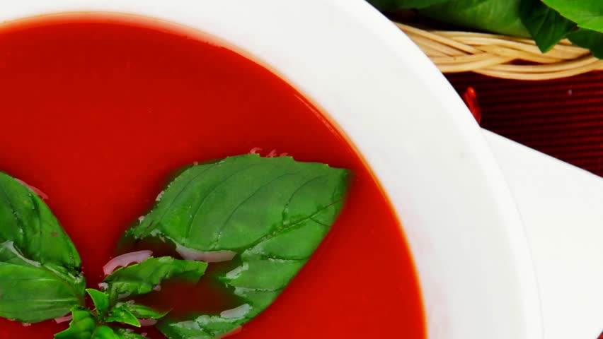 cold fresh diet tomato soup with basil thyme and dry pepper in big bowl over red mat on wood table ready to eat 1920x1080 intro motion slow hidef hd